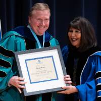 Recipient stands with President holding award and smiling